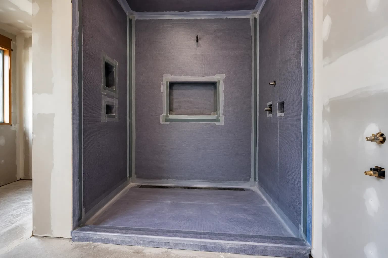 Shower waterproofing membrane covering walls, corners, and floor before tile installation